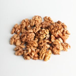 A majestic Juglans regia tree, the Common Walnut, standing tall with its broad, rounded crown of green pinnate leaves and developing nuts.